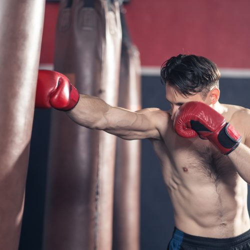 Caucasian bodybuilder man shirtless athlete wear boxing gloves, doing boxing workout exercise